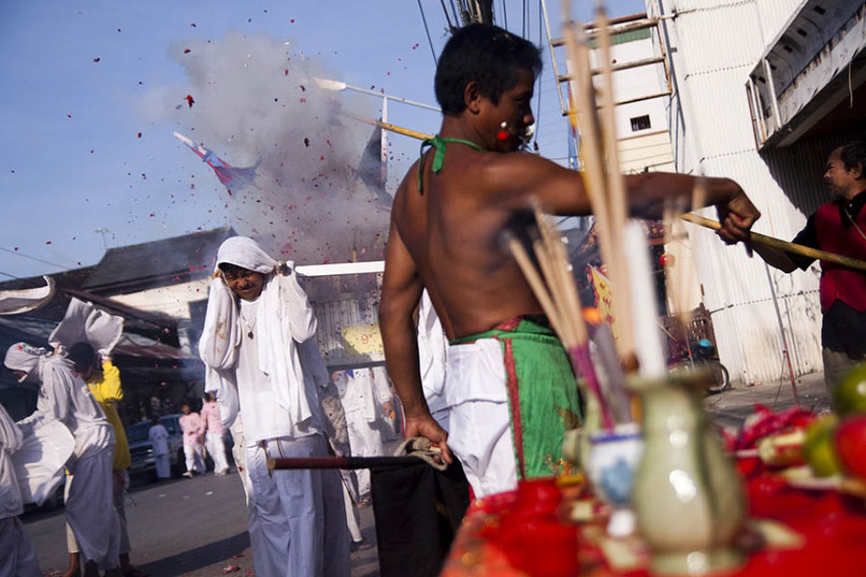 A ma-song blesses a shrine while firecrackers explode over the procession