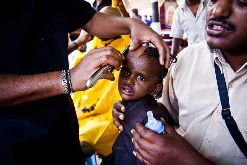 Young girl having head shaved during festival