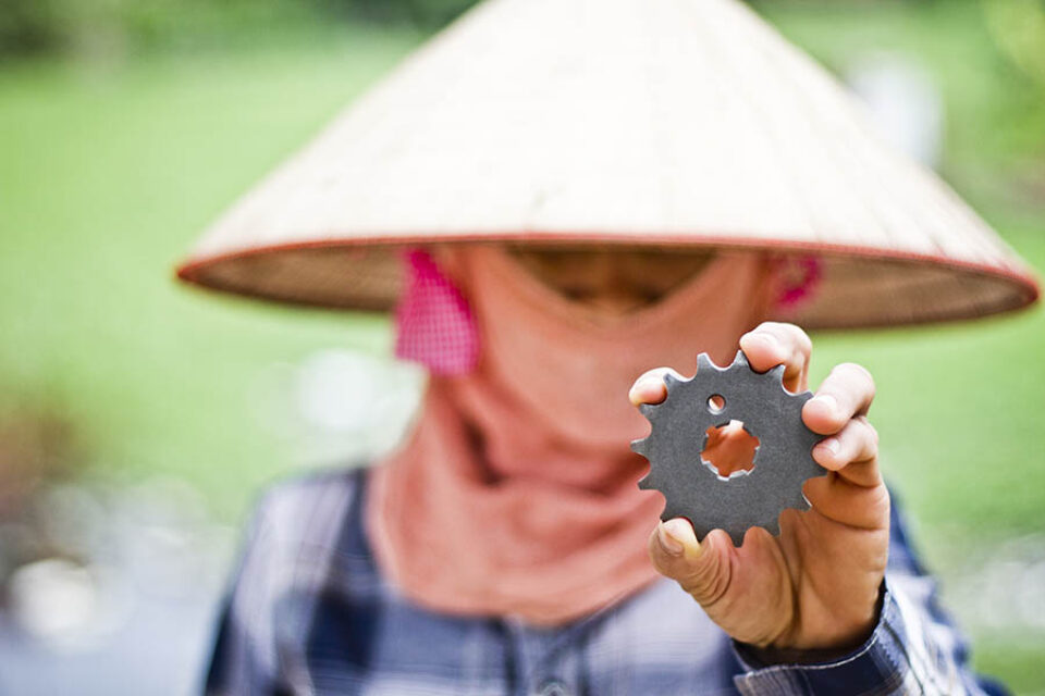 Woman in conical hat holding cog