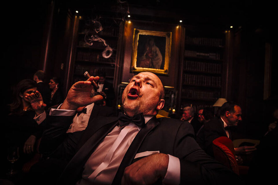 A man smokes a cigar at a formal event