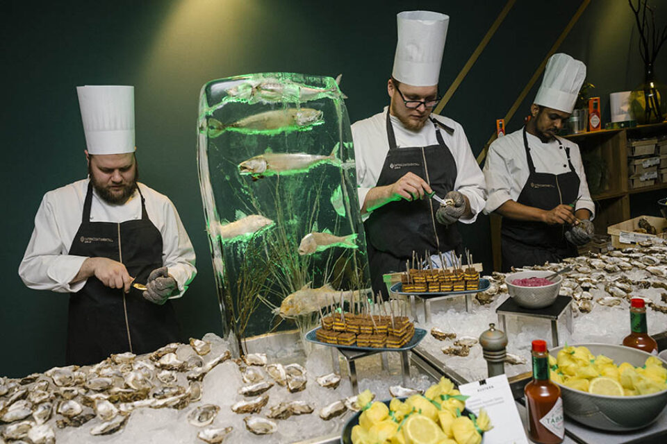 Chefs shuck oysters at a gala dinner food station