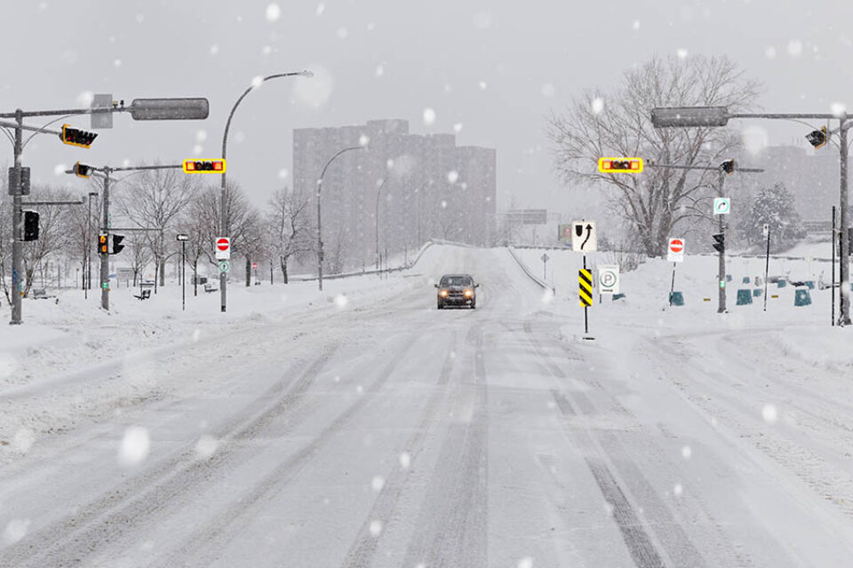 A lone car on a snowy road in Longueuil, Quebec, Canada