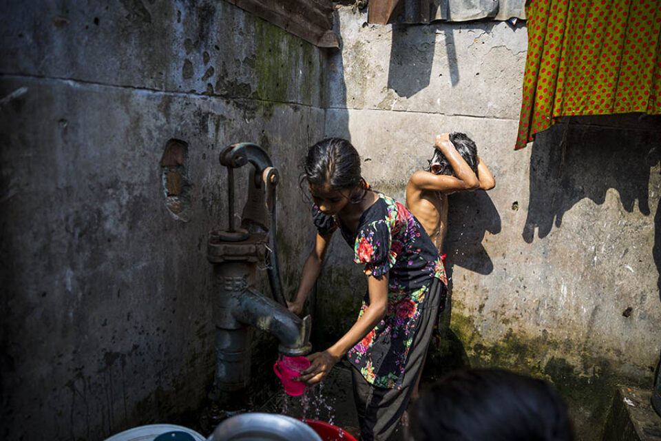 Young girls using water pump
