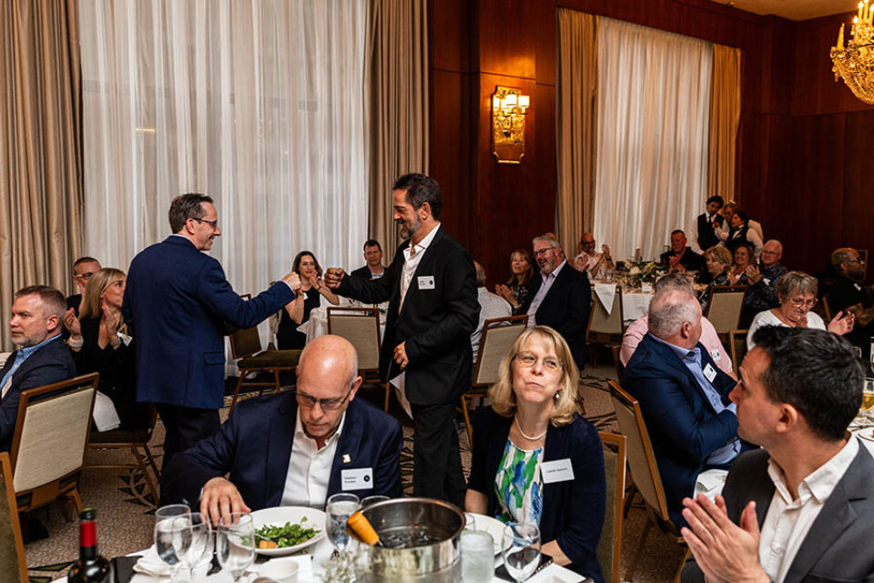 Event guests congratulate an awardee at a business ceremony