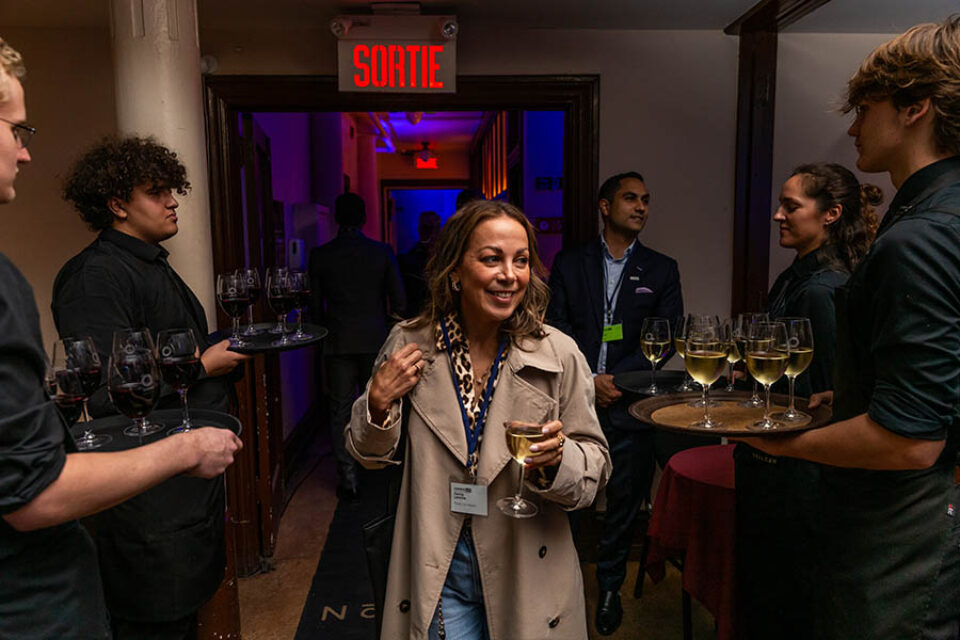 A woman takes a drink when entering a corporate networking event